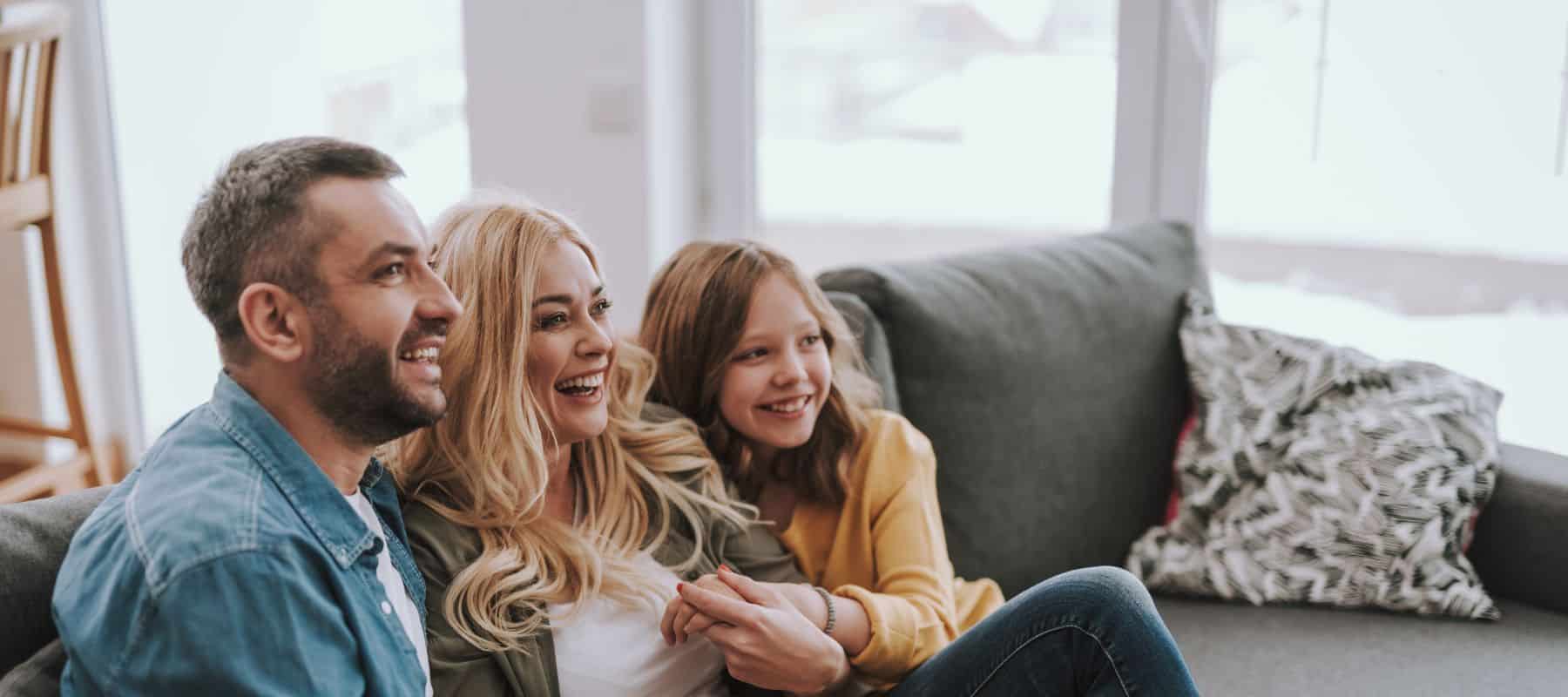 happy family sitting on a couch smiling and enjoying their comfortable home