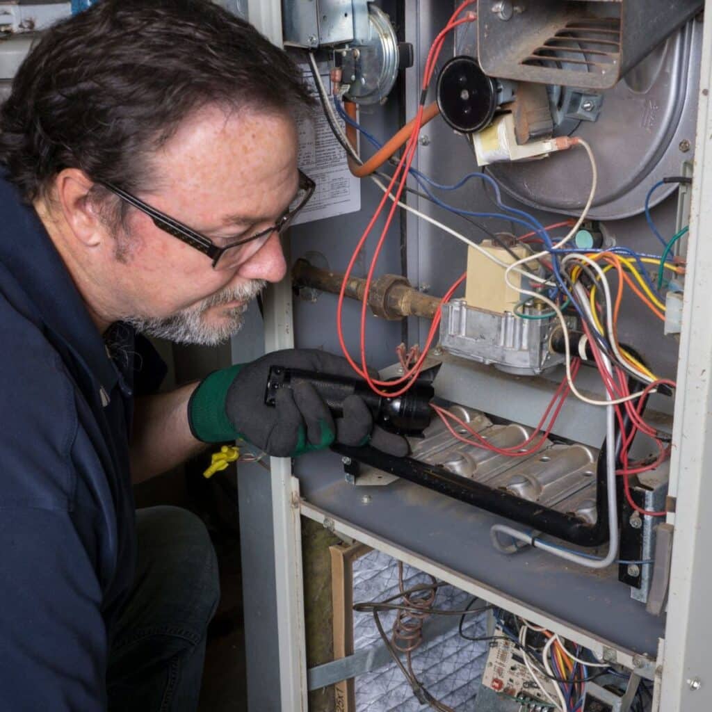 technician performing heater repair on a furnace inside a home