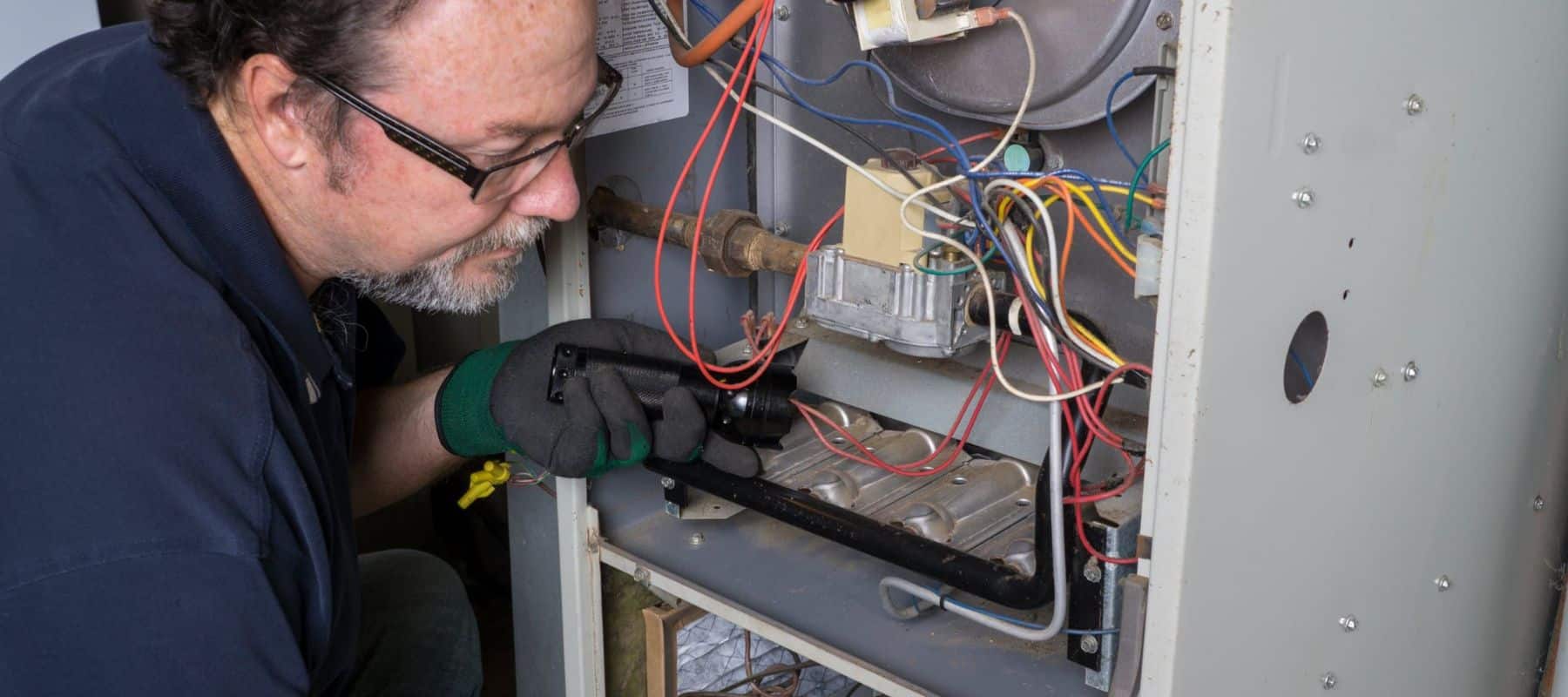 technician performing heater repair on a furnace inside a home