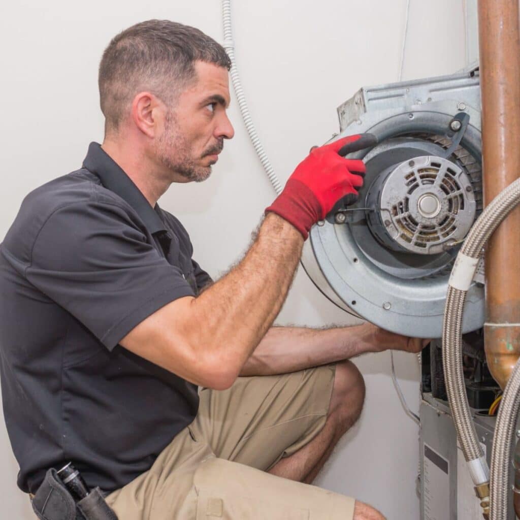 technician replacing part of a furnace inside a home