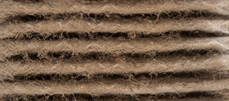 close up of a dirty, dusty air filter that has turned brown