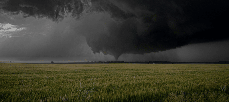 tornado preparing to touchdown on horizon near an open, grassy field