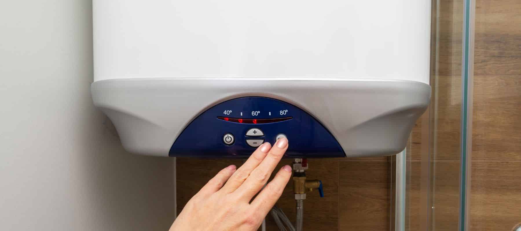 hand pressing button on blue and white tankless water heater to adjust the temperature settings