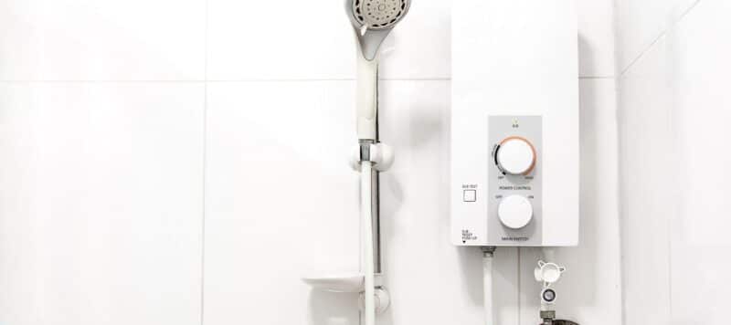closeup of a water heater installed right next to a removable showerhead ll