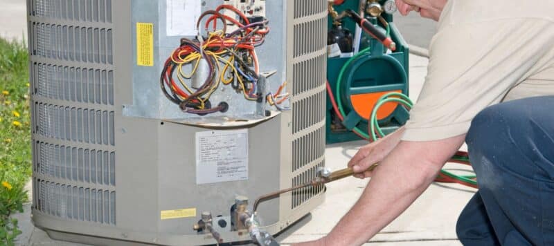 closeup of a technician performing repairs on an outdoor hvac unit